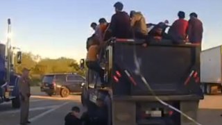 Migrants exit the back of a dump truck Tuesday in Cotulla, Texas.