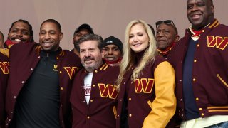 Team co-owners Dan and Tanya Snyder pose for a photo with current team members and alumni during the announcement of the Washington Football Team’s name change to the Washington Commanders at FedExField on February 02, 2022 in Landover, Maryland.