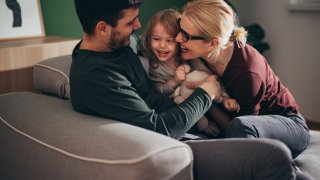 Mom and Dad Cuddling With Daughter