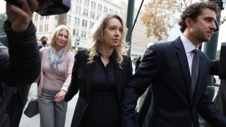 Former Theranos CEO Elizabeth Holmes (C) arrives at federal court with her partner Billy Evans (R) and mother Noel Holmes on November 18, 2022 in San Jose, California.