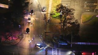 Aerial shot of a police investigation in Acton. It is a dark street with some trees on either side of the intersection