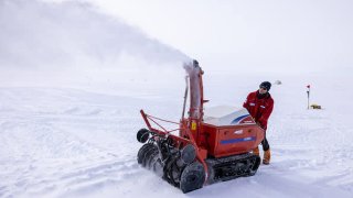 Martin Leonhard of the East Greenland Ice-Core Project (EastGRIP) operates snow blower putting a new snow floor for the winter-storage weather port tent at EastGRIP camp on August 9, 2022. EastGRIP is an international science station on the Greenland ice sheet, the second-largest ice body in the world after the Antarctic ice cap.