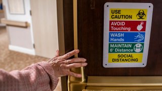 Tina Sandri, CEO of Forest Hills of DC senior living facility, passes a COVID-19 informational sign while walking to her office