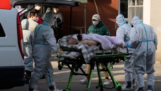 An elderly man on a stretcher is wheeled into the fever clinic