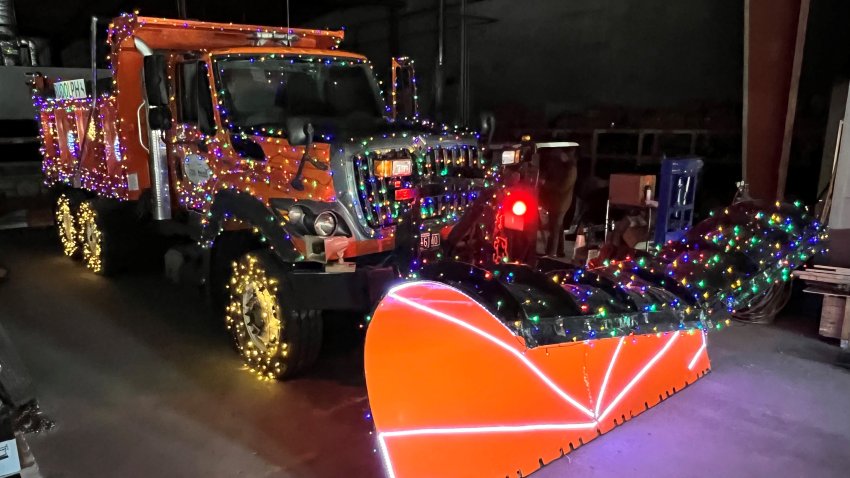 A snow plow covered in holiday lights