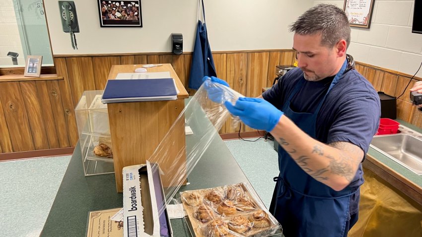 A man wrapped cinnamon buns with plastic wrap on a coffee shop counter