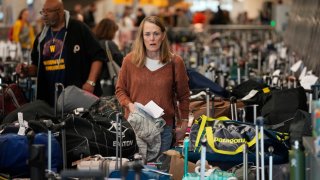 FILE - A traveler wades through a field of unclaimed bags at the Southwest Airlines luggage carousels at Denver International Airport, Dec. 27, 2022, in Denver. With its flights now running on a roughly normal schedule, Southwest Airlines is turning its attention to luring back customers and repairing damage to a reputation for service after canceling 15,000 flights around Christmas. The disruptions started with a winter storm and snowballed when Southwest's ancient crew-scheduling technology failed.