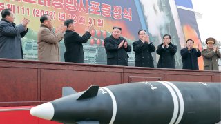 FILE - In this photo provided by the North Korean government, North Korean leader Kim Jong Un, center, attends a ceremony of donating 600mm super-large multiple launch rocket