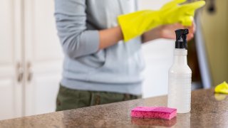 Woman Sanitizing the Counter with Disinfectant and Sponge