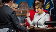 Maura Healey holds her hand on her family bible while being sworn into office by Senate Clerk Michael D. Hurley and Senate President Karen Spilka as Massachusetts' 73rd governor, making history as the first woman ever elected to the post and one of the nations first openly lesbian governors.