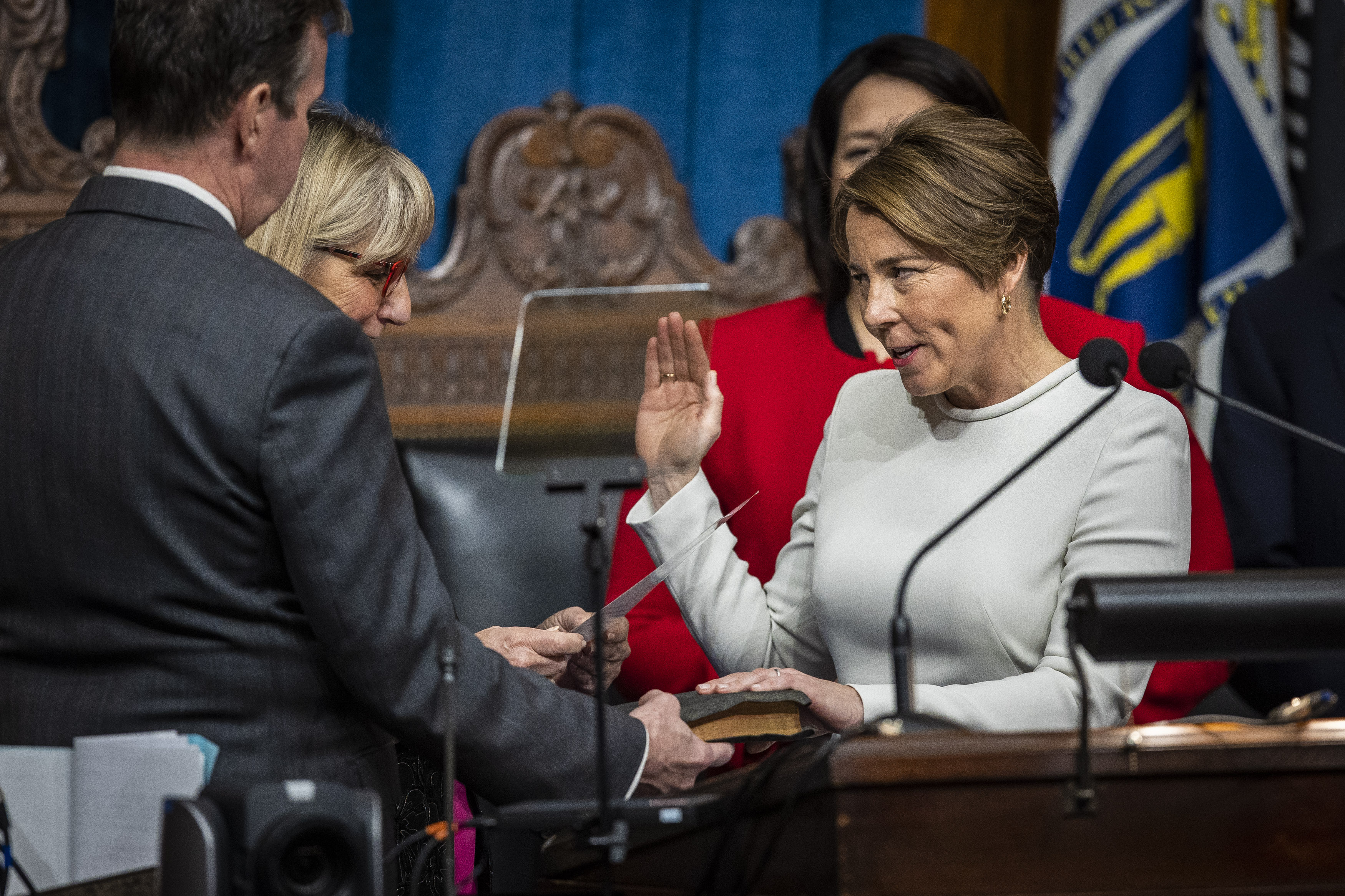 Maura Healey holds her hand on her family bible while being sworn into office by Senate Clerk Michael D. Hurley and Senate President Karen Spilka as Massachusetts' 73rd governor, making history as the first woman ever elected to the post and one of the nations first openly lesbian governors.