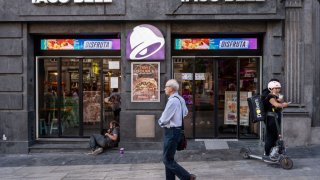 A pedestrian walks past the American chain of fast-food restaurants Taco Bell in Spain.