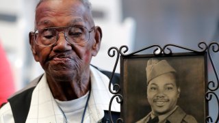 FILE – World War II veteran Lawrence Brooks holds a photo of him taken in 1943, as he celebrates his 110th birthday at the National World War II Museum in New Orleans, on Sept. 12, 2019. For Veterans Day, a group of Democratic lawmakers is reviving an effort to pay the families of Black servicemen who fought on behalf of the nation during World War II for benefits they were denied or prevented from taking full advantage of when they returned home from war. (AP Photo/Gerald Herbert, File)