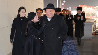 In this photo provided by the North Korean government, North Korean leader Kim Jong Un, front right, with his daughter and his wife Ri Sol Ju, left, attend a military parade to mark the 75th founding anniversary