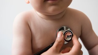 Doctor listening to chest of baby boy with stethoscope