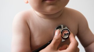Doctor listening to chest of baby boy with stethoscope