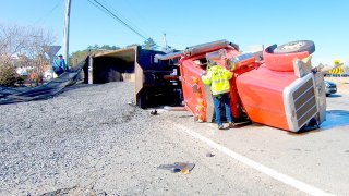 A rolled-over dump truck spilled gravel on the Bourne Rotary in Bourne, Massachusetts, on Tuesday, March 21, 2023.