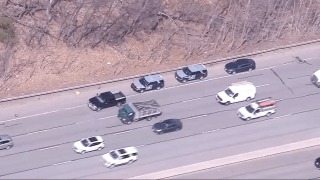 Massachusetts State Police cruisers on the side of Interstate 95 on Friday, March 31, 2023, investigating an unattended death in the woods nearby.