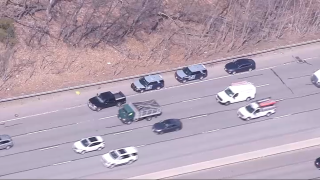 Massachusetts State Police cruisers on the side of Interstate 95 on Friday, March 31, 2023, investigating an unattended death in the woods nearby.