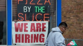 A hiring sign is displayed at a restauran