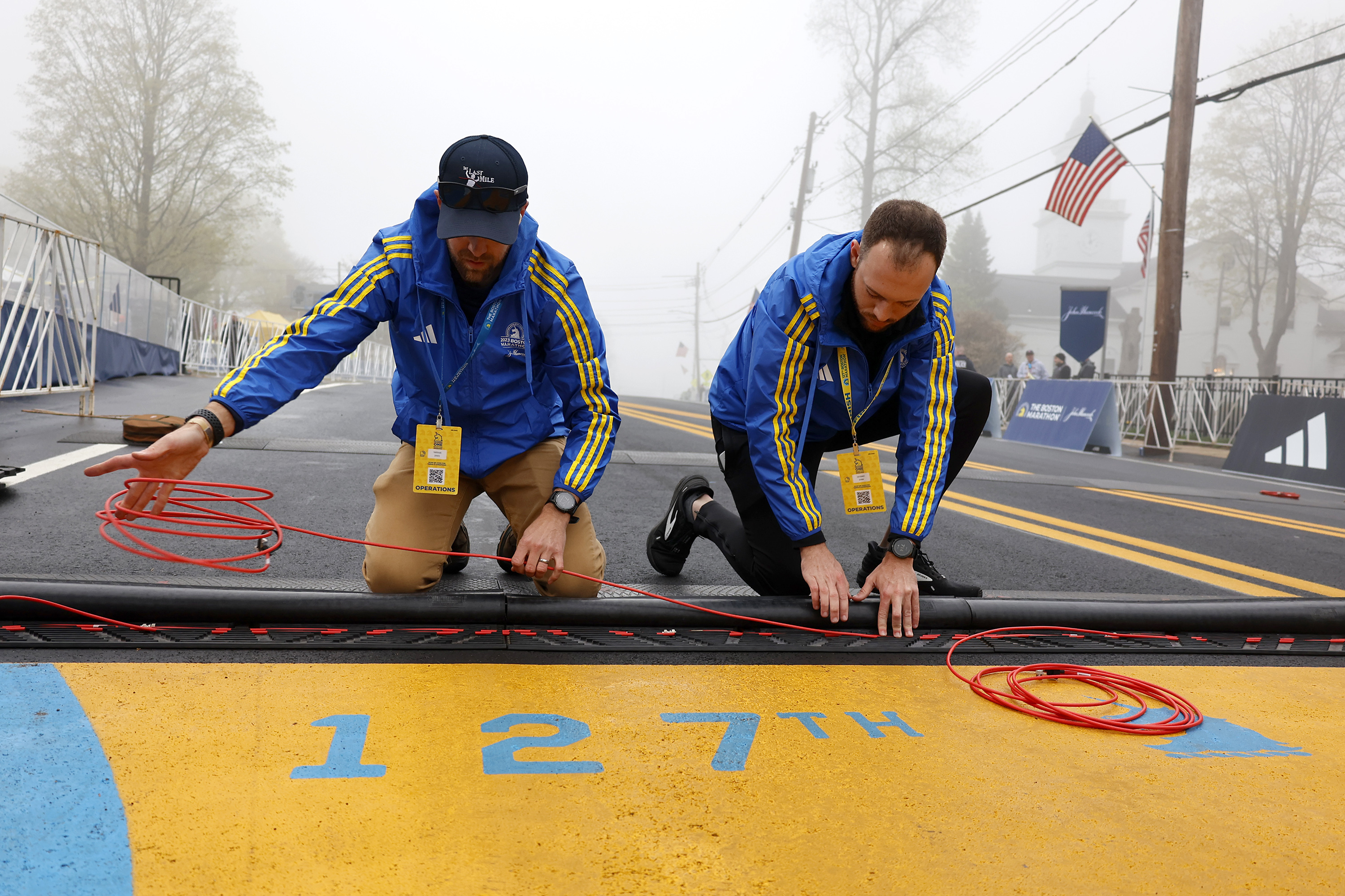 Race operations workers install the timing mat at the starting line of the 127th Boston Marathon, Monday, April 17, 2023, in Hopkinton, Mass.