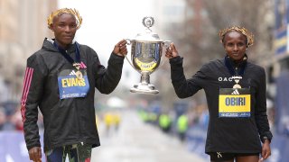 Evans Chebet and Hellen Obiri, both of Kenya, pose with the trophy on the finish line after winning the professional Men's Division and professional Women's Division respectively during the 127th Boston Marathon on April 17, 2023 in Boston, Massachusetts.