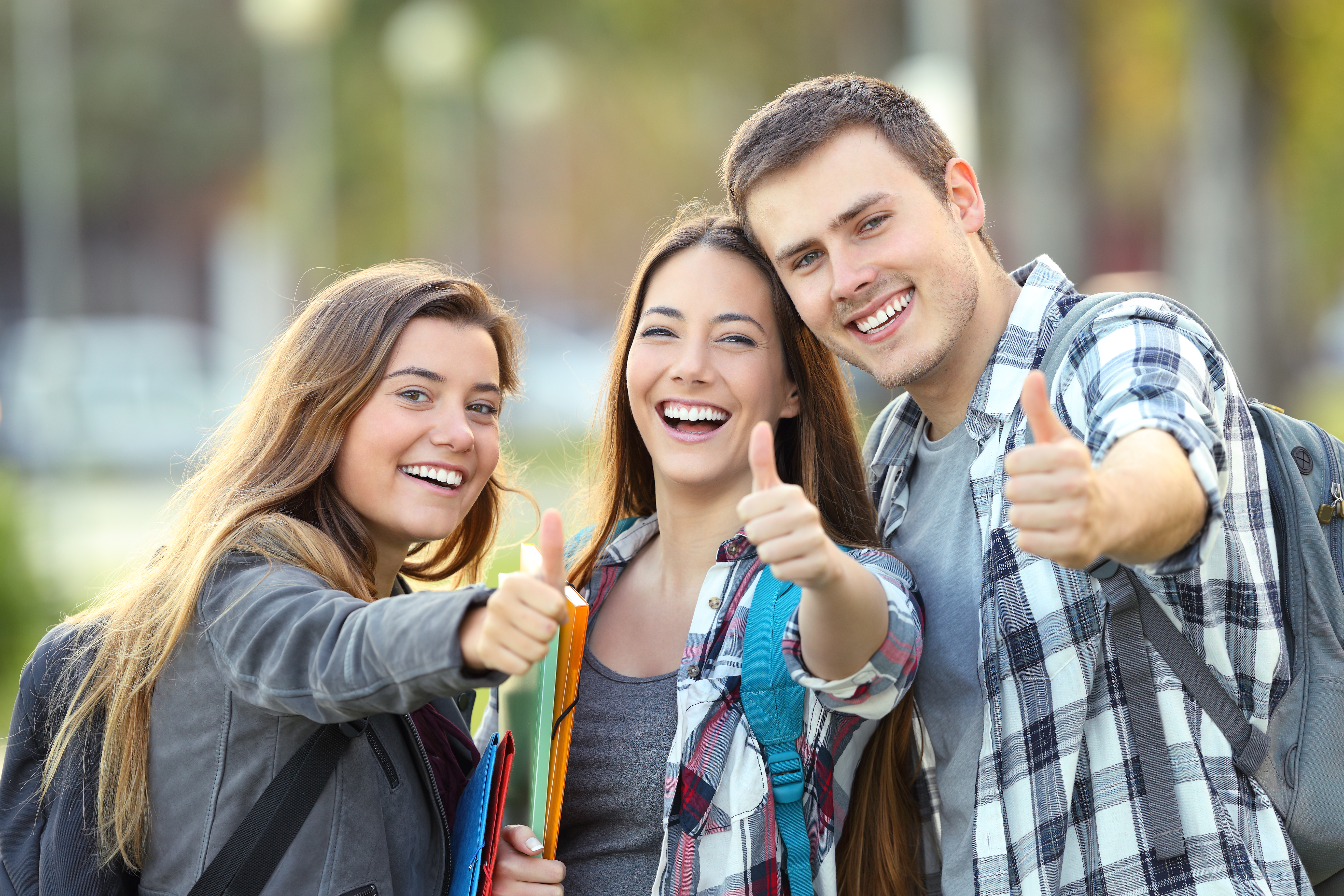 A stock image, captioned, "Three happy students looking at you with thumbs up in an university campus," that appears in the Massachusetts Central University website. 