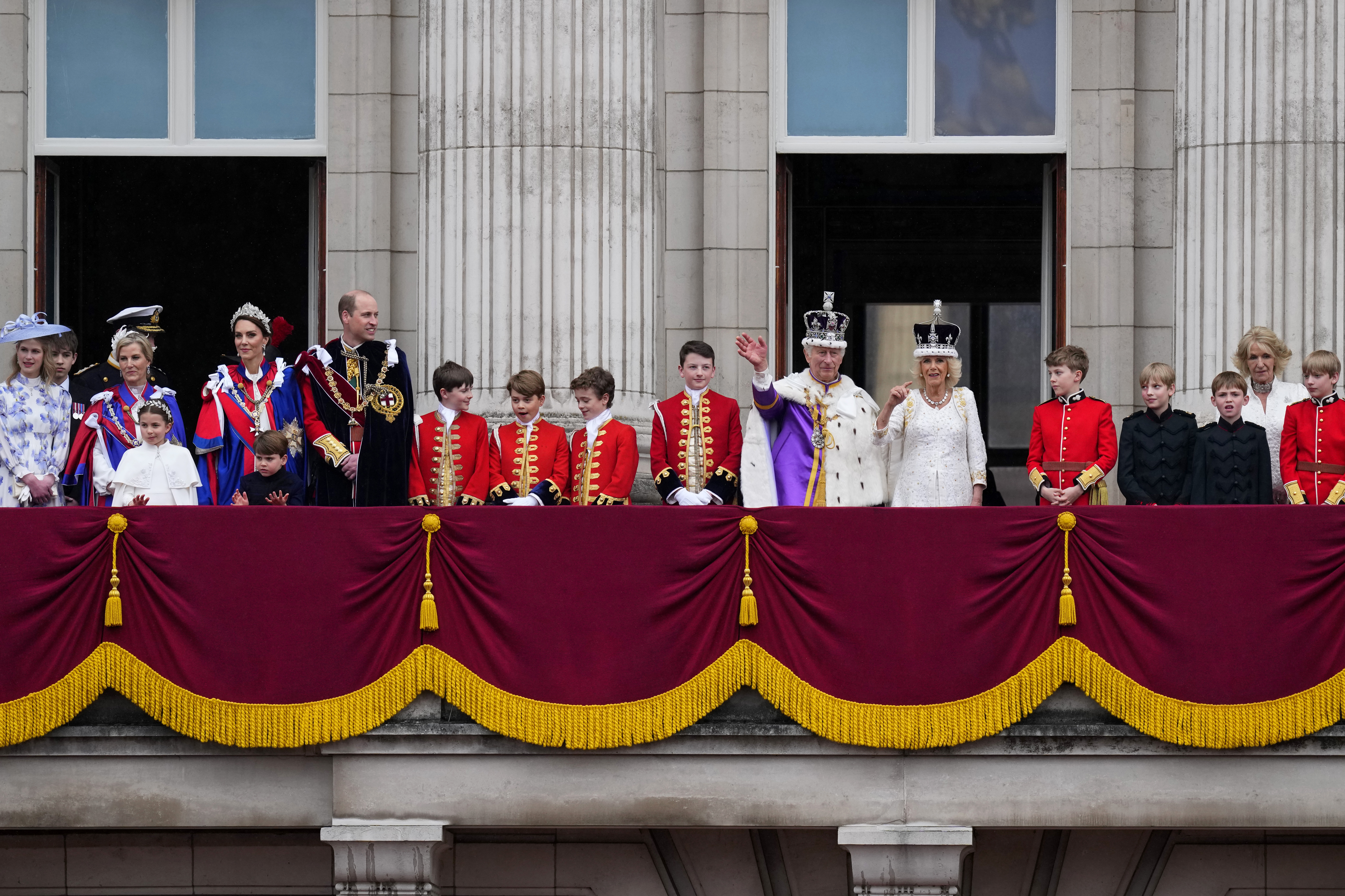 Britain’s King Charles III and Queen Camilla, along with their pages and other working royals, wave to the crowds from the balcony of Buckingham Palace after their coronation ceremony, in London, Saturday, May 6, 2023.