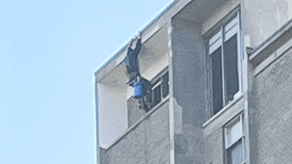 A window-washer dangling from the roof at a Brookline apartment building on Wednesday, May 17, 2023.