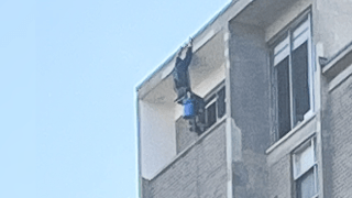 A window-washer dangling from the roof at a Brookline apartment building on Wednesday, May 17, 2023.