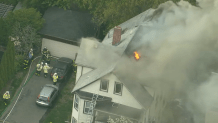 Flames visible in a house fire in Watertown, Massachusetts, on Thursday, May 11, 2023.