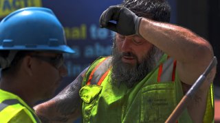 Boston, MA – August 9: Construction worker Michael Elder took his hard hat off to wipe sweat off his face while working on the MBTA Green Line in 90-plus degree weather.