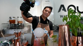 JC, mixologist, blows smoke bubbles atop a gourmet water cocktail he is preparing at the AQUA Water Bar by LUQEL in Dubai, United Arab Emirates, Tuesday, July 11, 2023.