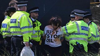 Police detain a protestor from Just Stop Oil, by the 17th green on day two of the 151st British Open Golf Championship at Royal Liverpool Golf Course in Hoylake, north west England on July 21, 2023.