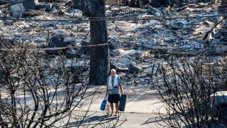 A man stands among the wreckage in downtown Lahaina, Maui, on Thursday, August 11, 2023.