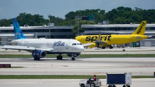 A JetBlue Airways Airbus A320, left, passes a Spirit Airlines Airbus A320 as it taxis on the runway