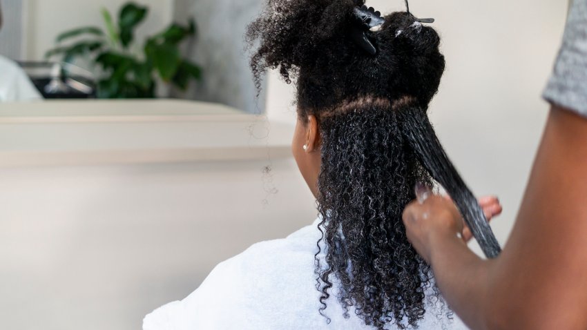 File Photo. A Black girl gets her hair relaxed at a salon.