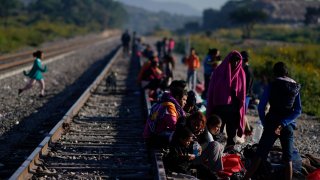 Migrants wait along the rail lines