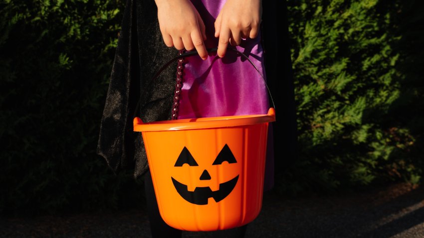 A bucket in the form of a pumpkin in children’s hands. Halloween. Candy or death. Pumpkin. Holiday. Masquerade. Halloween. Candy or death. Pumpkin. Holiday. Masquerade.