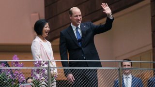 Britain's Prince William, right, waves as with Sim Ann, Senior Minister of State for Foreign Affairs of Singapore