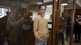 US journalist Evan Gershkovich stands inside a defendants' cage.