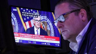 A trader works, as a screen displays a news conference by Federal Reserve Board Chairman Jerome Powell following the Fed rate announcement, on the floor of the New York Stock Exchange (NYSE) in New York City, U.S., December 13, 2023.