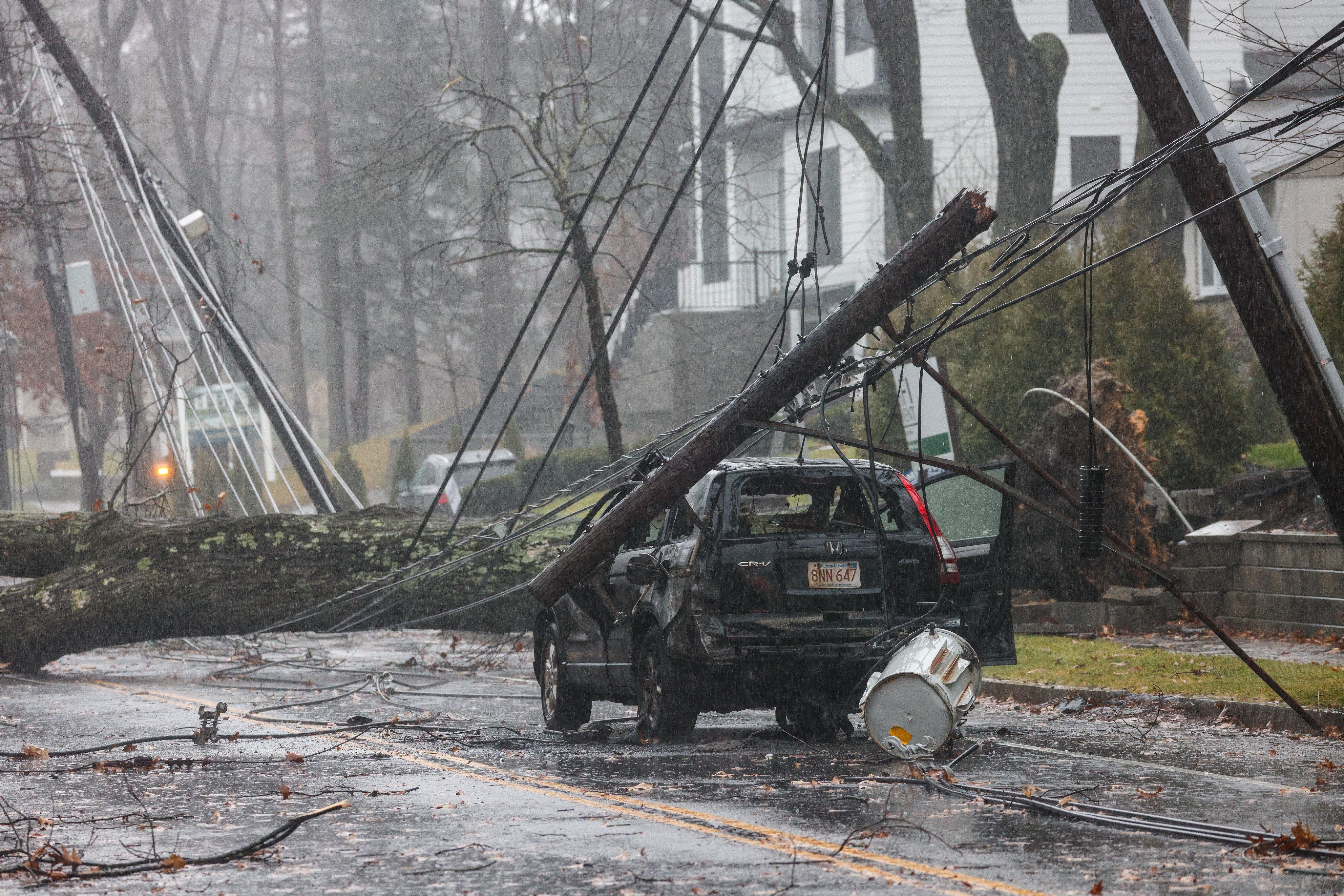 A tree fell on power lines, damaging an SUV as well, on Dedham Street in Newton, Massachusetts, as a storm hit the region on Monday, Dec. 18, 2023.