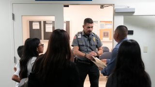 An officer listens to a question as he directs people to a courtroom, Wednesday, Jan. 10, 2024, in an immigration court in Miami.