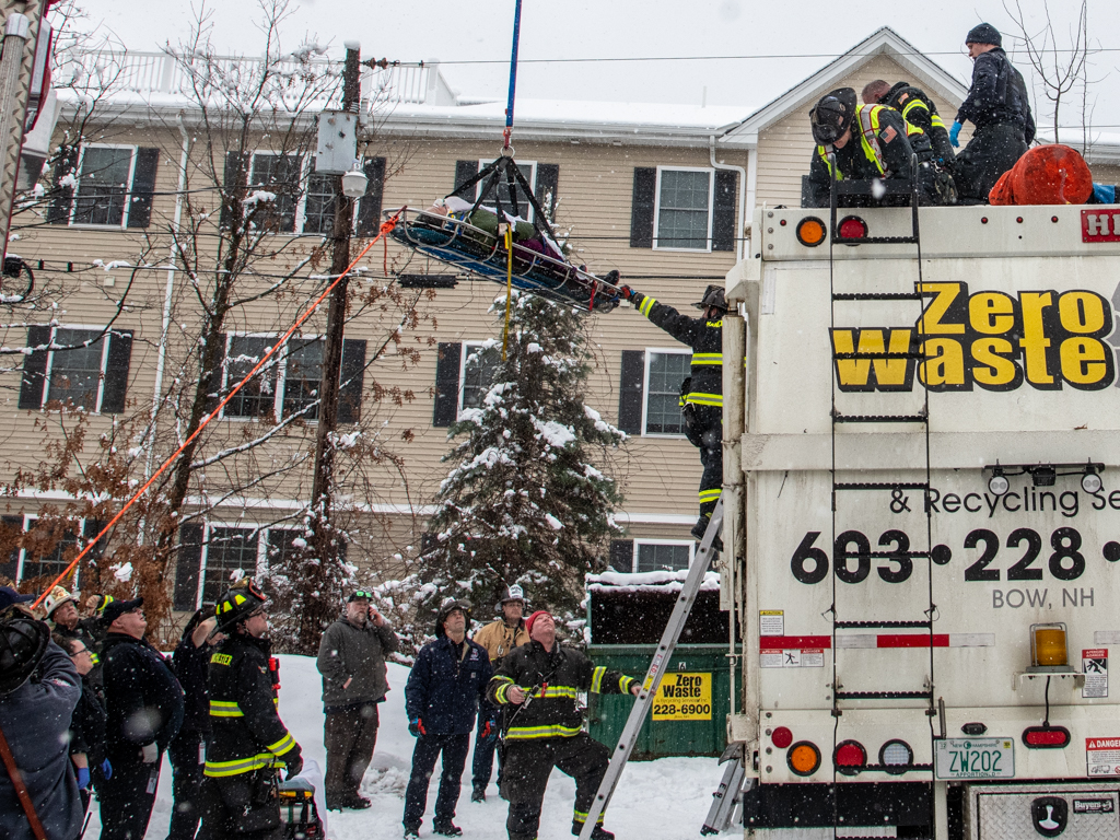 A woman being hoisted from a sanitation truck she'd been trapped inside in Manchester, New Hampshire, on Monday, Jan. 29, 2024.