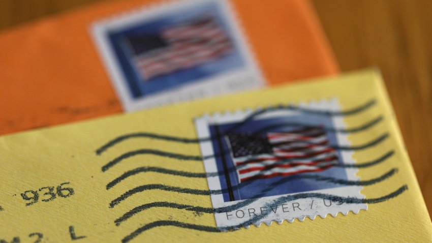 U.S. Postal Service (USPS) forever stamps are seen on orange and yellow envelopes