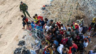 As seen from an aerial view a U.S. Border Patrol agent supervises as immigrants walk into the United States after crossing the Rio Grande from Mexico on September 30, 2023 in Eagle Pass, Texas.