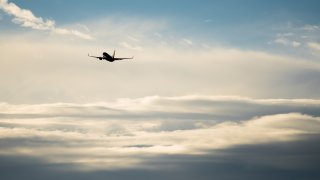 Silhouette airplane flying in the sky surround by blue cloud.