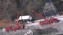 Cranes working to lift a crashed truck from the side of I-495 in Harvard, Massachusetts, on Wednesday, Feb. 21, 2024.