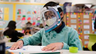 FILE – A student wears a mask and face shield in a 4th grade class amid the COVID-19 pandemic at Washington Elementary School on Jan. 12, 2022, in Lynwood, Calif.